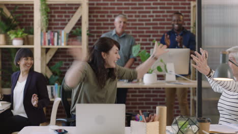 young business woman arms raised celebrating surprise corporate success laughing cheerful enjoying colleagues cheering in office workspace