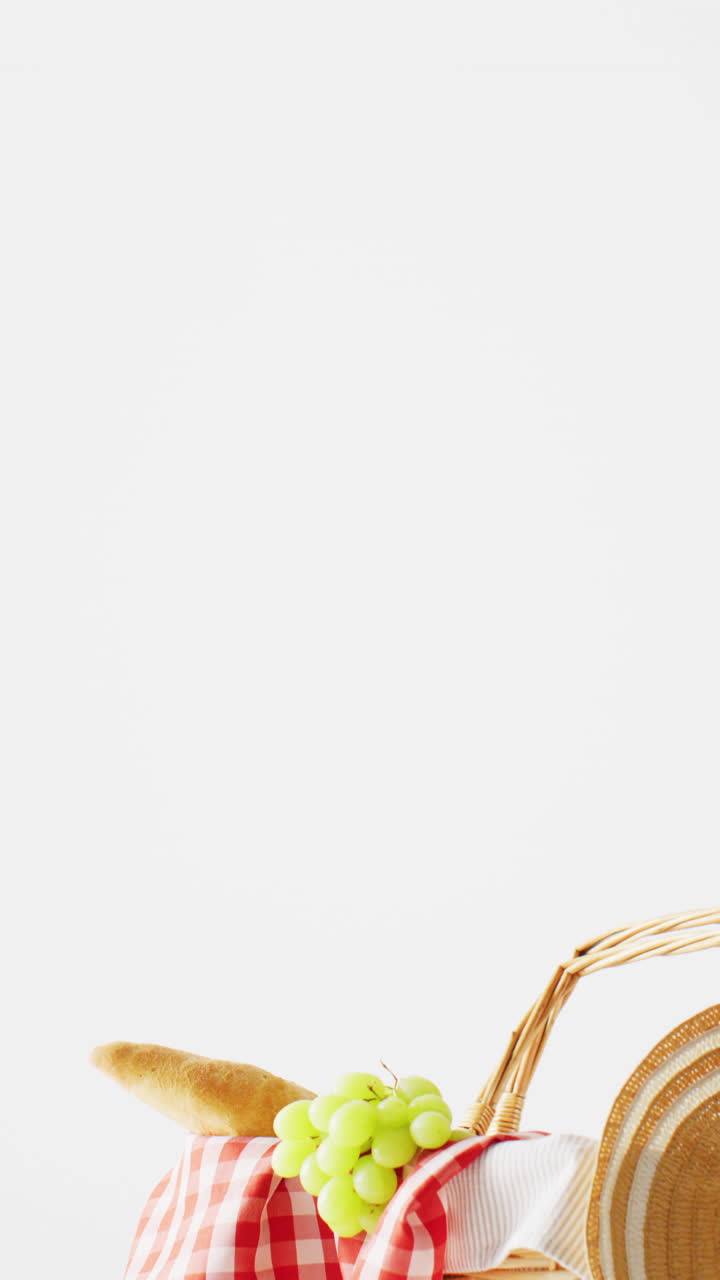 Vertical video of basket with food and gingham tablecloth, copy space on white background