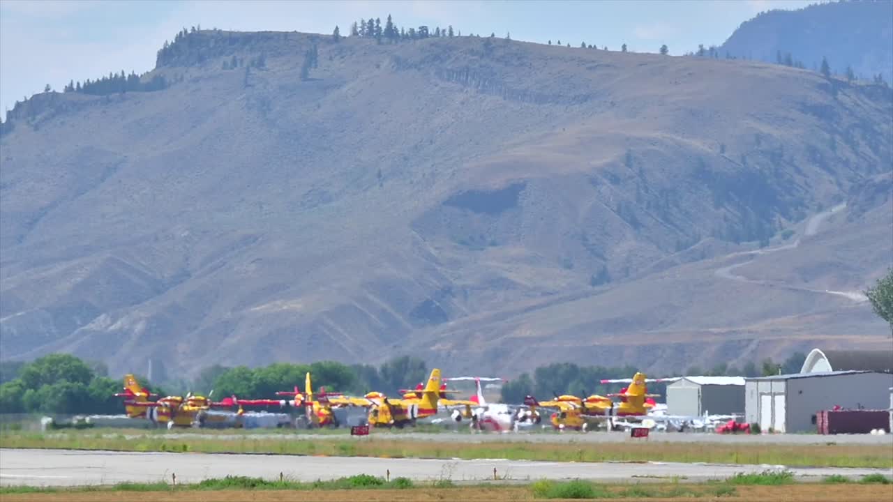 소방 항공기 의 함대 가 연기 로 뒤 ⁇ 인  ⁇ 루프 공항 에서 기다리고 있다