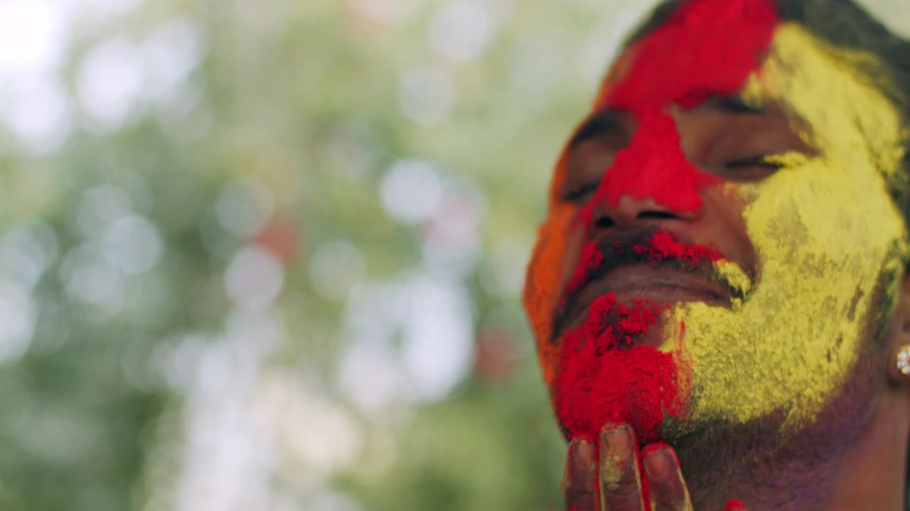 hombre indio de primer plano de la cara manchada con colores brillantes de holi