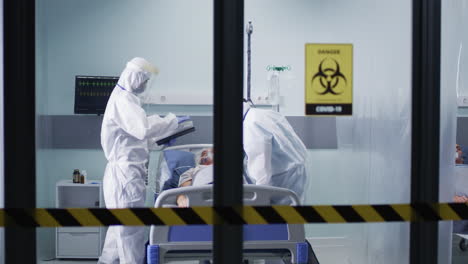 healthcare workers in ppe attend to covid-19 patients in hospital icu