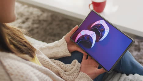 caucasian woman using tablet at home for online shopping, game controllers on screnn,slow motion