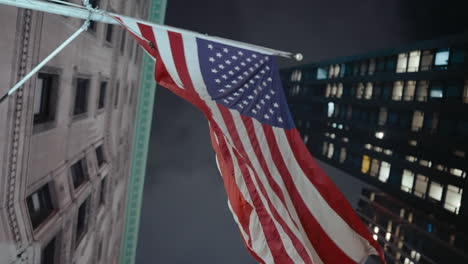 american flag flying over city buildings at night