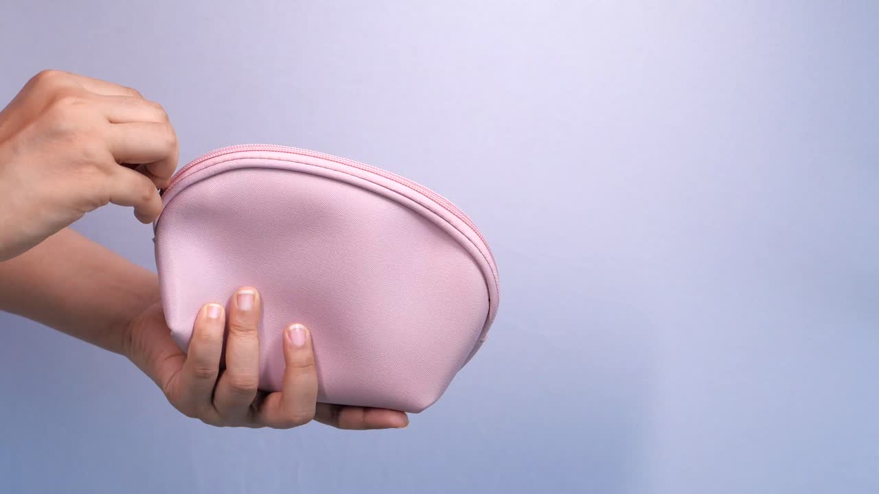 mujer sosteniendo una bolsa de cosméticos rosa vacía