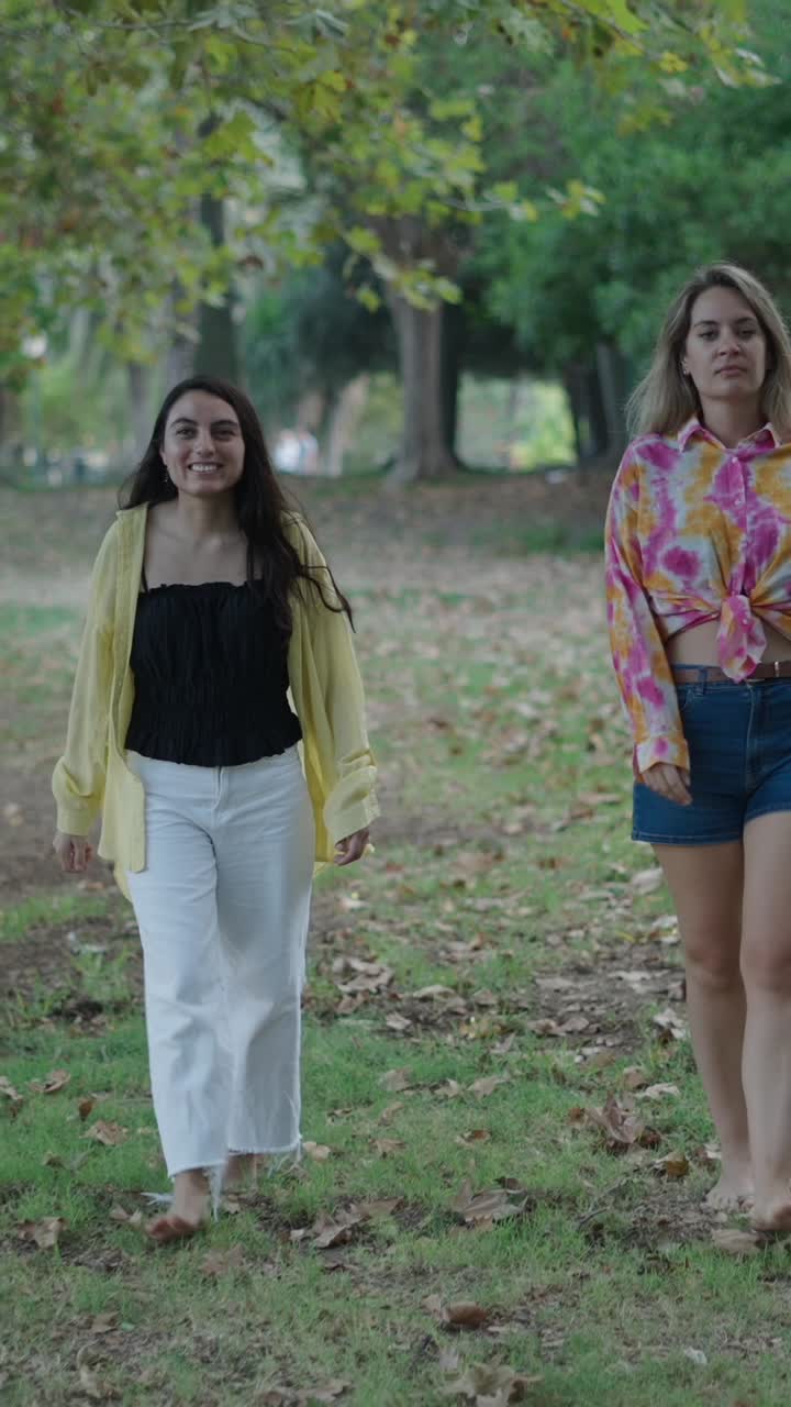 Two women walking barefoot in a park