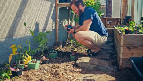 a man with a beard planting in the pot inside the greenhouse. static shot
