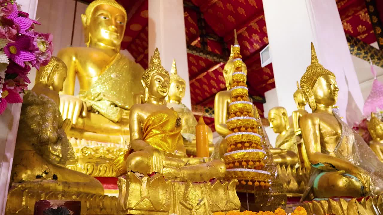 Golden Buddha statues in Wat Arun, Bangkok, illuminated by warm lighting, showcasing intricate details and serene expressions