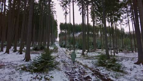Girl-in-a-thick-winter-jacket-walks-along-a-forest-path-covered-with-snow