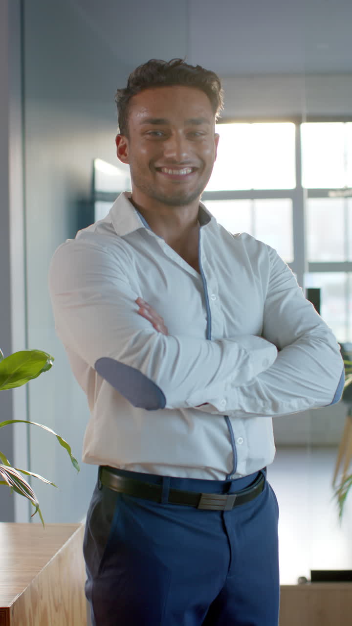 Vertical video of portrait of latino businessman smiling at office, slow motion