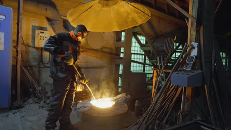 worker managing the molten metal pouring from industrial furnace at a foundry