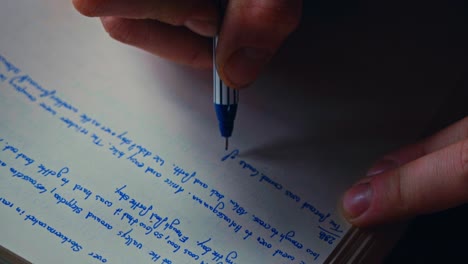 closeup of a person writing on paper using a pen with blue ink