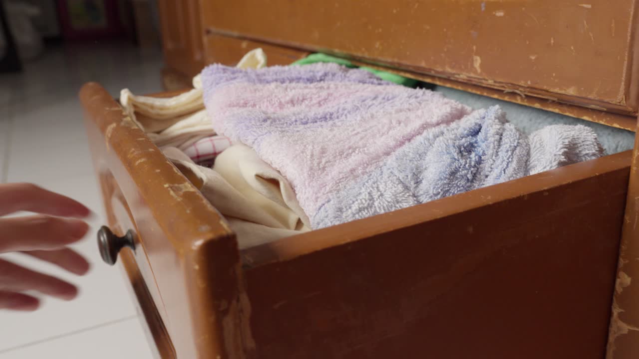 Hand pulling open a weathered wooden drawer in a well-lit room, close-up