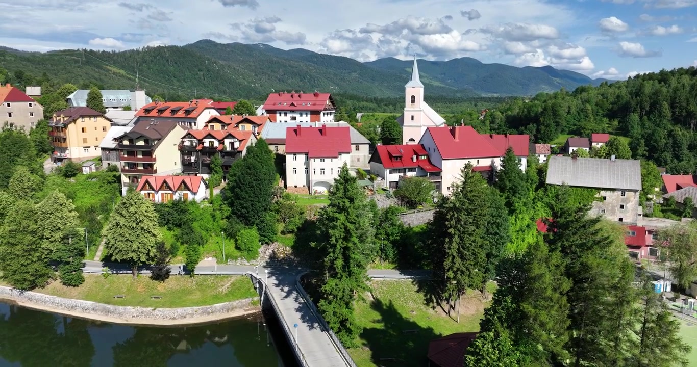 Lotnicze ujęcie wprowadzające wioski Fužine w Chorwacji, tradycyjne budynki nad jeziorem, zieleń, panorama gór.