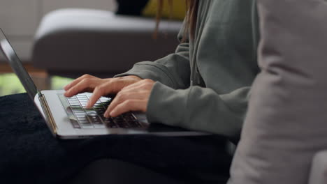 close up of anxious woman sitting indoors on sofa working from home using laptop worried about cost of living crisis 1