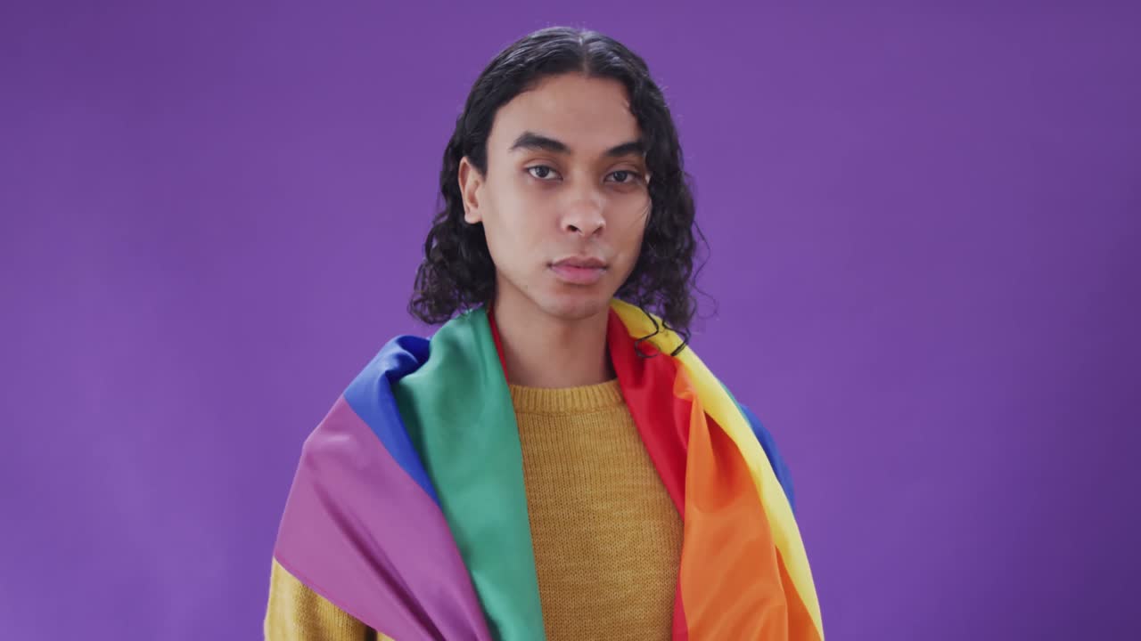 Portrait of happy biracial man holding lgbt flag and posing