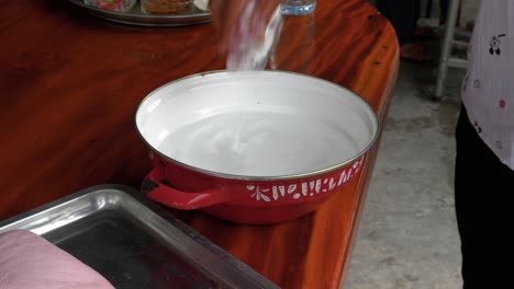verter sal en un recipiente de acero con agua directamente de una bolsa de plástico