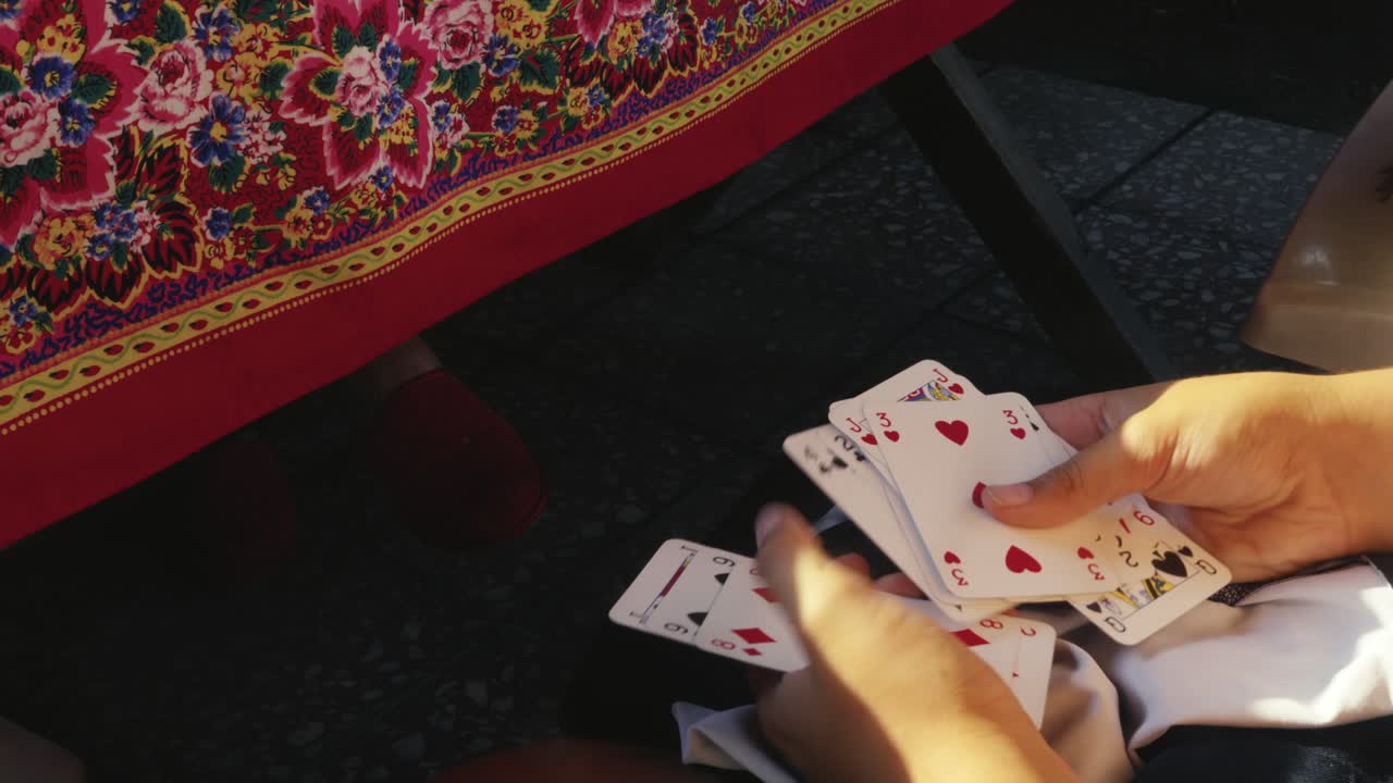 Young hands counting playing cards under family game table