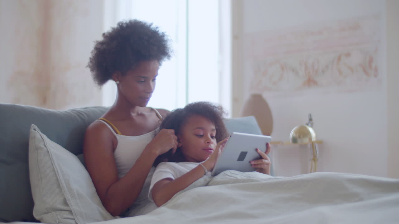 African American mother and daughter lying in bed and relaxing