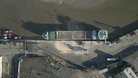 top down aerial view of container ship unloading shipment from cargo depot