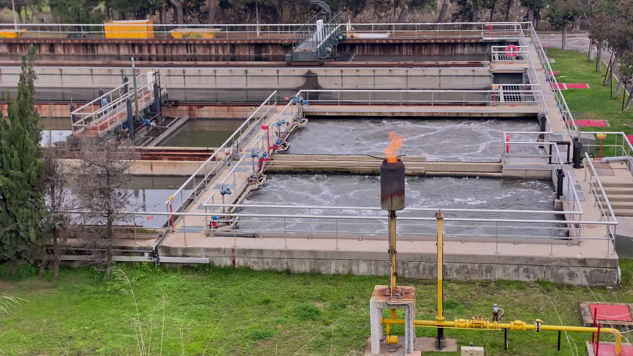 Wastewater treatment plant system with aeration tanks and a biogas flare burning excess gas, ensuring environmental management
