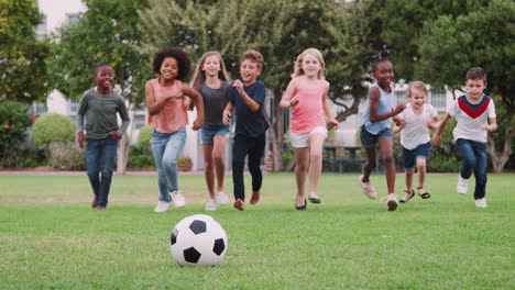 group of children playing football with friends in park