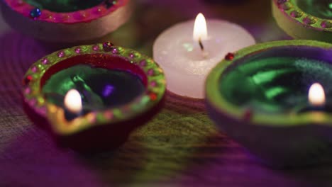 lit candles in decorative clay pots and tea light candle on wooden table top, bokeh background