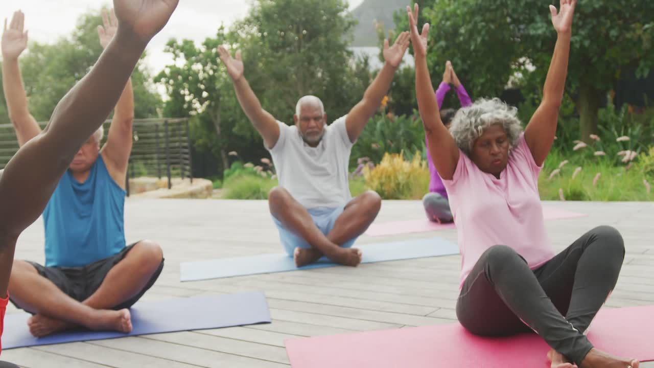 Happy senior diverse people practicing yoga in garden at retirement home