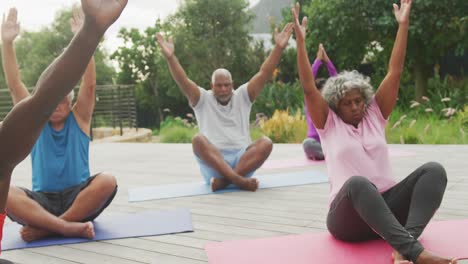 happy senior diverse people practicing yoga in garden at retirement home