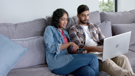 una joven pareja asiática compra en línea desde casa usando una computadora portátil.