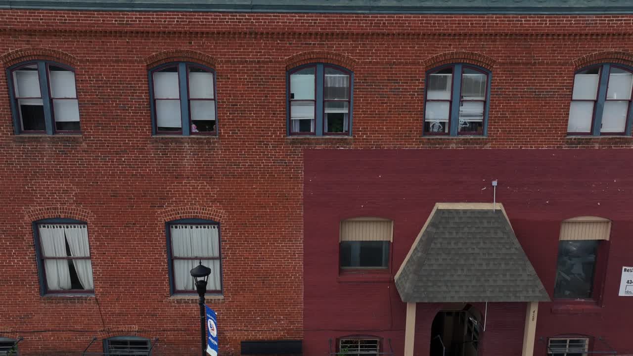 Descending drone shot of american town with old Buildings. Red brick facade and colorful trees in autumn. Sunset time in small quaint city of USA. Wide shot.