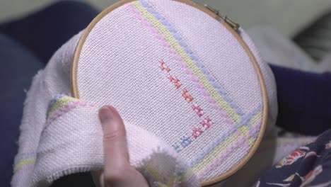 close-up shot of a woman cross-stitching effortlessly creating a pattern