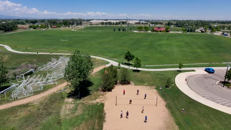 a park filled with people playing volleyball and riding on bike paths