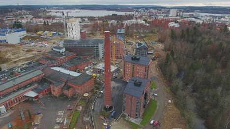 aerial shot of a red brick chimney of an old factory in middle of a construction site