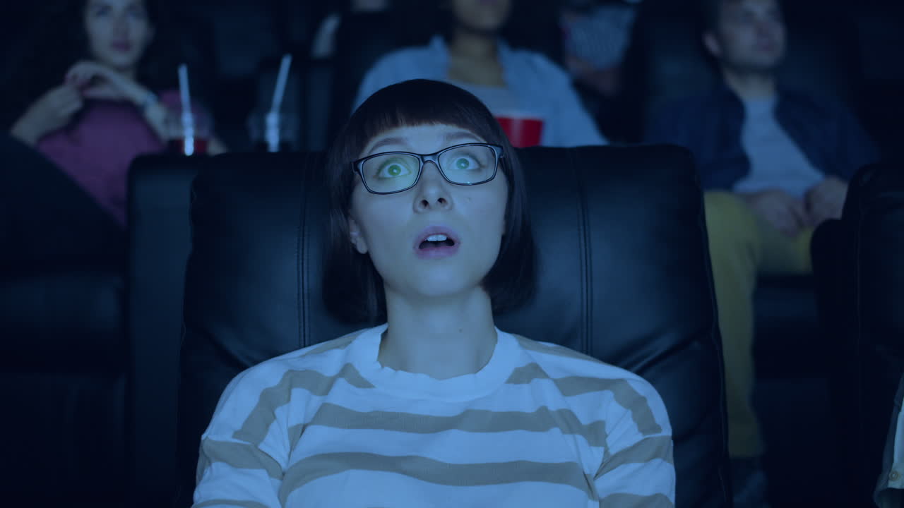Woman watching a movie in a cinema and surprised