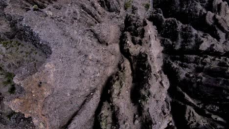 Top-down-drone-shot-flying-over-the-edge-of-a-cliff-with-rugged-edges-in-Jujuy,-Argentina