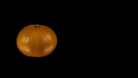 food: orange fruit revolves, isolated on black background, left side