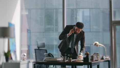 financial manager speaking mobile phone standing workplace looking notes on desk