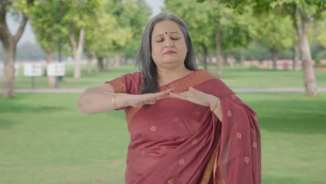 happy indian old woman doing breathe in breathe out exercise in park