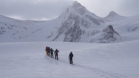 Colorful-group-of-backcountry-skiers-ascending-towards-mountain-in-the-mist