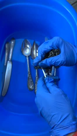 washing silverware in a blue basin