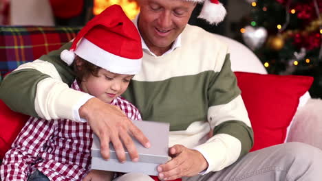 son giving father a christmas gift on the couch