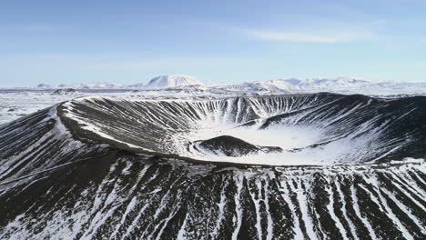 toma aérea del volcán hverfjall en islandia y las montañas circundantes cubiertas de nieve.