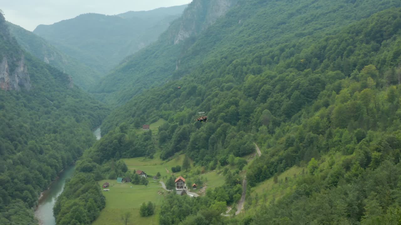 la gente se desliza a lo largo de la tirolesa sobre el bosque en montenegro