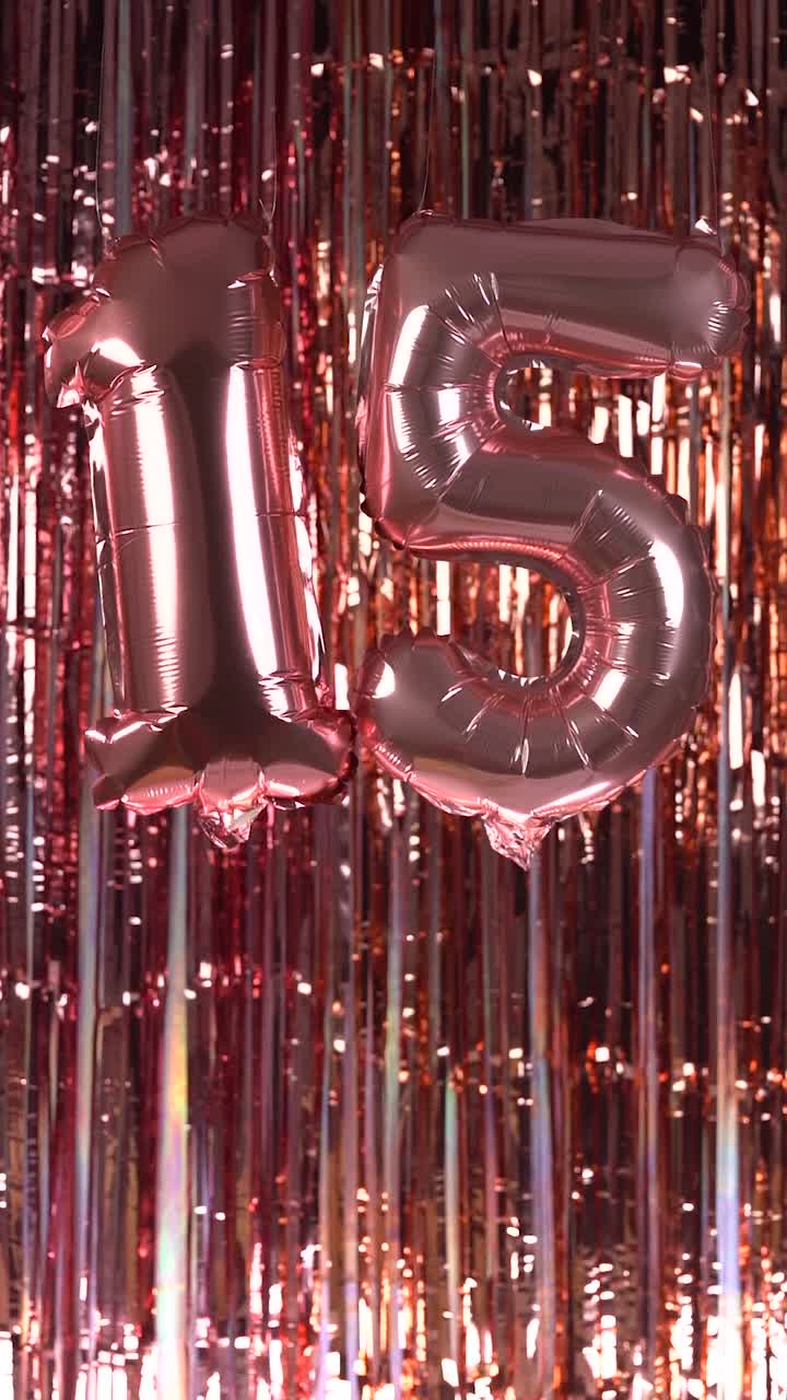 Palloncini color oro rosa numero 15 che ondeggiano su uno sfondo scintillante di fili metallici