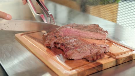 closeup of a chef cutting a medium rare flank beef