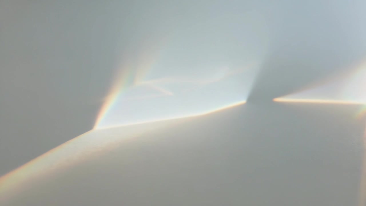 Shifting prism light across wall, forming tri or trap patches and rainbow rims, angles shifting