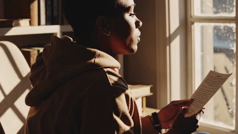 person reading a letter by a window
