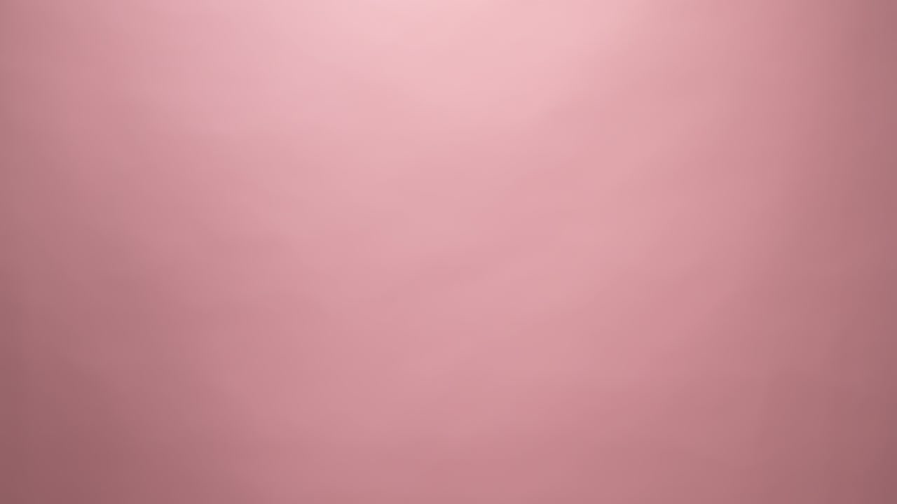 cerca de la mano sosteniendo el despertador en fondo rosa.