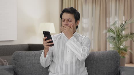 Tired-Indian-man-scrolling-phone