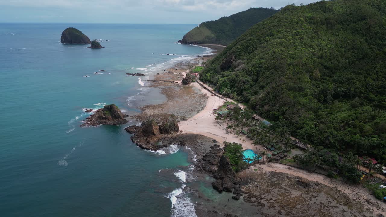 A captivating drone shot captures a winding road running parallel to the sand, with the ocean stretching out to one side.